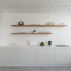 a kitchen with white cabinets and shelves on the wall