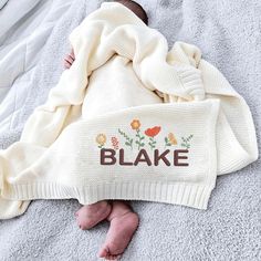 a baby wrapped in a blanket with the word blake on it's chest