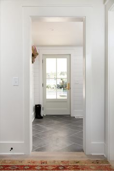 an entryway with tile flooring and white walls, leading to a front door