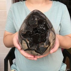 a person holding a rock in their hands with black stuff on it's surface