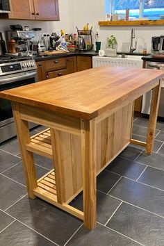 a kitchen island made out of wood in the middle of a tile flooring area