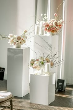 three tall white vases with flowers and candles