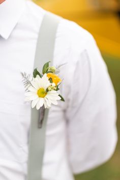 a close up of a person wearing a white shirt with suspenders and a flower in his lapel