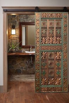 an open door leading to a bathroom with stone walls and wood floors, along with a sink