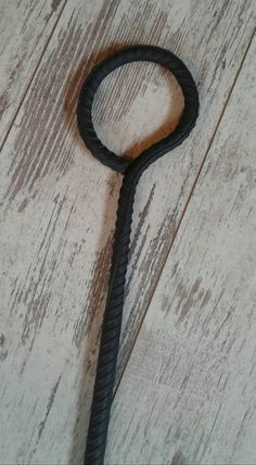 a close up of a metal hook on a wooden floor with wood planks behind it