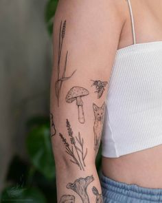 a woman's arm with tattoos on it and various plants, mushrooms, and birds