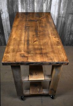 a wooden table sitting on top of a cement floor in front of a wall covered with wood planks