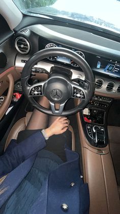 a woman is sitting in the driver's seat of a mercedes benz car with her hands on the steering wheel