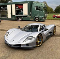 a silver sports car parked in front of a truck