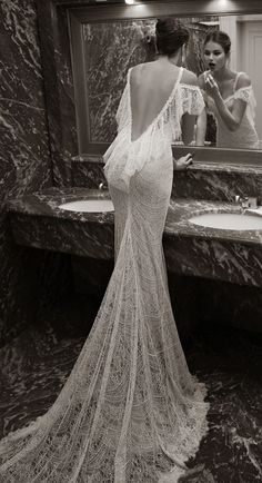 a woman taking a selfie in front of a bathroom mirror wearing a wedding dress