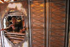 a man standing in front of a mirror on the side of a building with rust