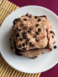 a white plate topped with chocolate cake covered in frosting