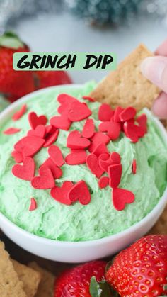 a bowl filled with green dip surrounded by crackers and strawberries on the side