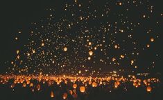 the sky is filled with lots of lanterns in the dark, as people look on