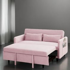 a pink couch with two pillows on it and a pull out bed in the middle