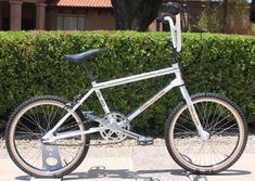 a white bicycle parked in front of a hedge