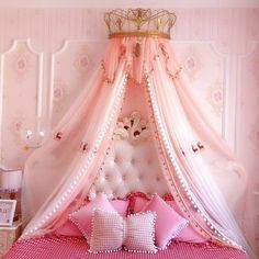 a bed with pink and white bedspread, pillows and a canopy over it