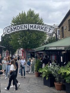 people are walking down the street under an arch that says camden market on it's side