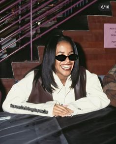 a woman sitting at a table wearing sunglasses