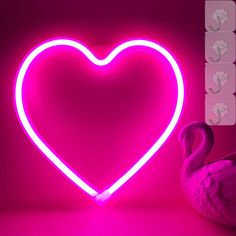 a pink heart shaped neon sign next to a flamingo