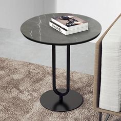 a black table with a book on it next to a white chair and a couch