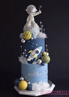 a three tiered cake with an astronaut on top and space related decorations around it