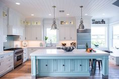 a kitchen with white cabinets and blue island