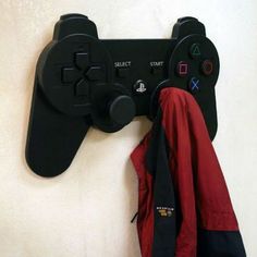 a video game controller mounted to the side of a wall next to a coat rack