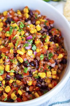 a white bowl filled with black beans, corn and cilantro salsa next to tortilla chips