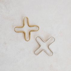 two pieces of gold and silver metal on a white surface, one with an x in the middle