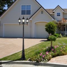 a large house with lots of flowers in the front yard and lights on each side