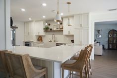 a kitchen with an island and bar stools next to the counter top in front of it