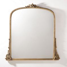 an ornate gold framed mirror hanging on the side of a wall with a white background