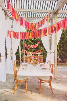 an outdoor dining area with tables and chairs under a canopy covered in white drapes