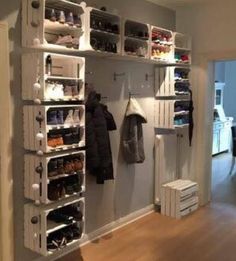 an open closet with shoes and clothes hanging on the wall next to a bed in a living room