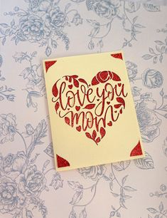 a card with the words love you mom written in red ink on a white background