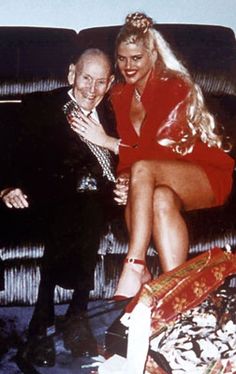 a man sitting next to a woman in a red dress on top of a couch