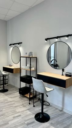 a hair salon with mirrors and stools in front of the counter top, along with two round mirrors on the wall