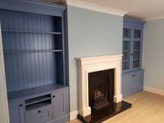 an empty living room with a fireplace and built - in bookshelves