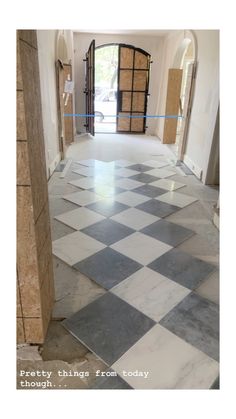 an empty hallway with black and white checkered tile on the floor next to a doorway