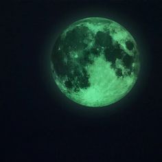 the full moon glows green in the dark sky