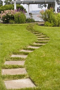 a stone path in the grass leading to a house