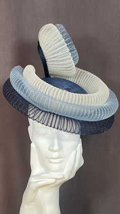 a white mannequin head with blue and grey hats on it