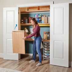 a woman standing in front of a desk with a laptop on it and holding the door open