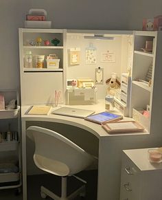 a white desk with a laptop on top of it next to a shelf filled with items