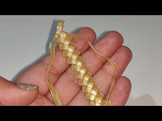 a hand holding a piece of gold colored thread