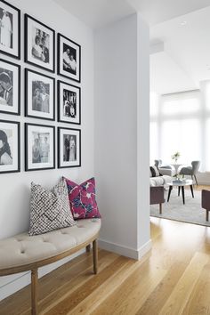 a living room filled with furniture and framed pictures on the wall above a wooden floor