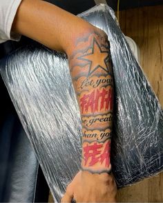 a man with a tattoo on his arm holding onto a silver foil wrapped chair cushion