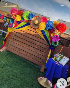 a colorful display on the grass in front of a wooden structure with paper flowers and fan decorations