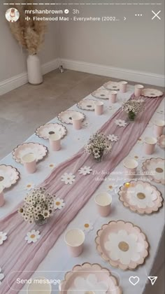 the table is set up with pink and white plates, cups, and vases